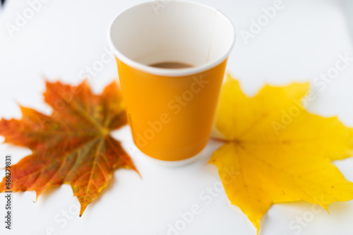 Yellow glass with coffee and autumn leaves.