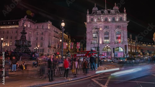 Timelapse of the Piccadilly Circus in London at night. People rushing through the streets of London with neon lights around them. photo