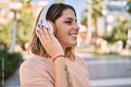 Young hispanic woman smiling confident listening to music at park