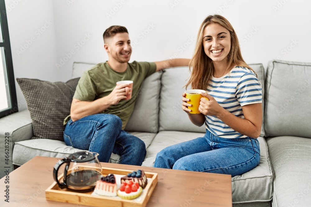Obraz premium Young hispanic couple smiling happy having breakfast sitting on the sofa at home.