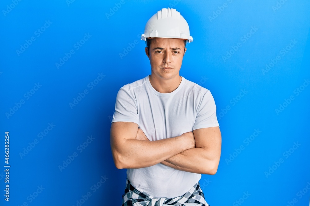 Handsome young man wearing builder uniform and hardhat skeptic and nervous, disapproving expression on face with crossed arms. negative person. Handsome young man wearing builder uniform and hardhat skeptic and nervous, disapproving expression on face with crossed arms. negative person.