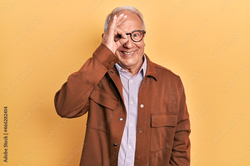 Senior man with grey hair wearing casual jacket and glasses doing ok gesture with hand smiling, eye looking through fingers with happy face. Senior man with grey hair wearing casual jacket and glasses doing ok gesture with hand smiling, eye looking through fingers with happy face.