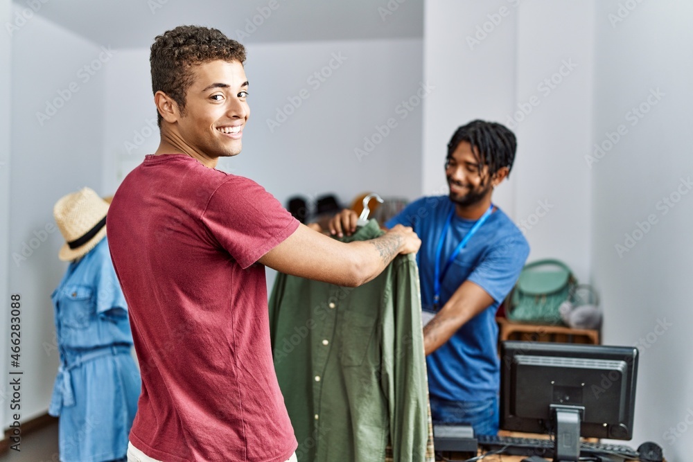Two men shopkeeper and customer choosing shirt at clothing store Two men shopkeeper and customer choosing shirt at clothing store