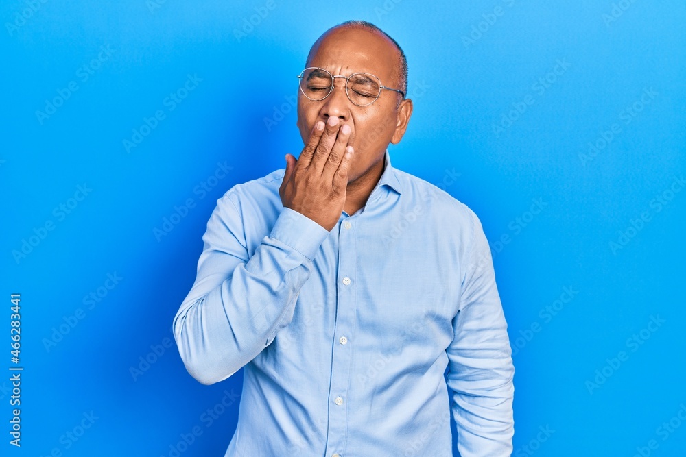 Middle age latin man wearing casual clothes and glasses bored yawning tired covering mouth with hand. restless and sleepiness.