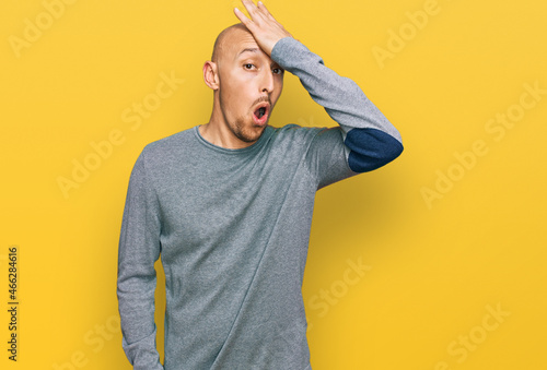 Bald man with beard wearing casual clothes surprised with hand on head for mistake, remember error. forgot, bad memory concept.