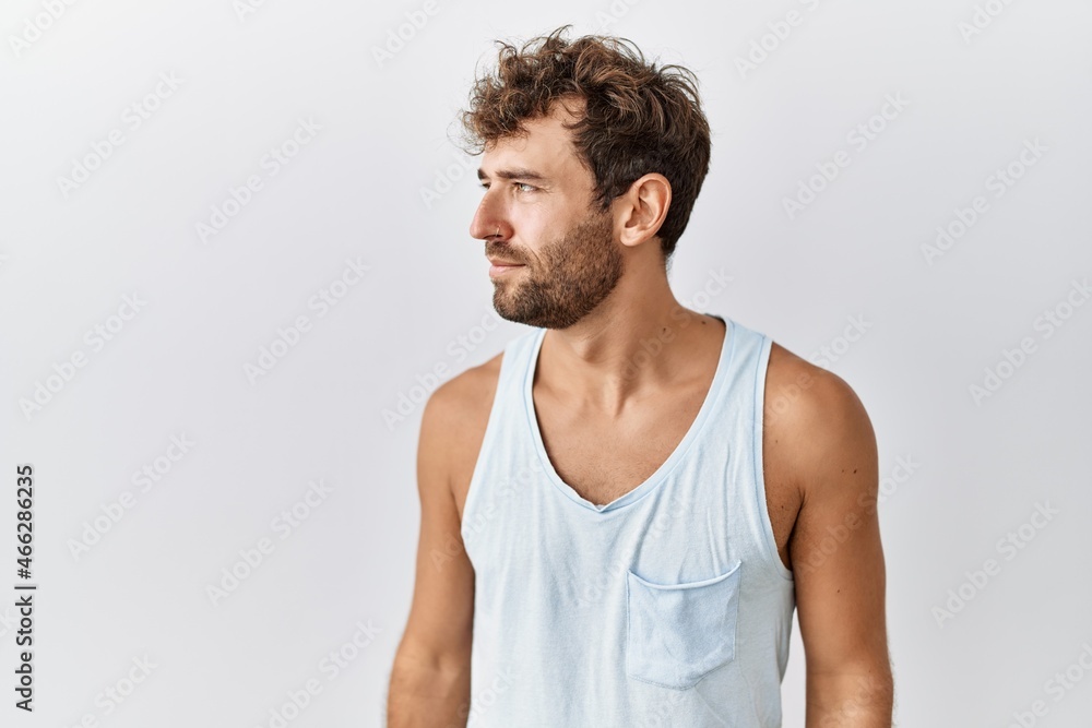 Obraz premium Young handsome man standing over isolated background looking to side, relax profile pose with natural face with confident smile.