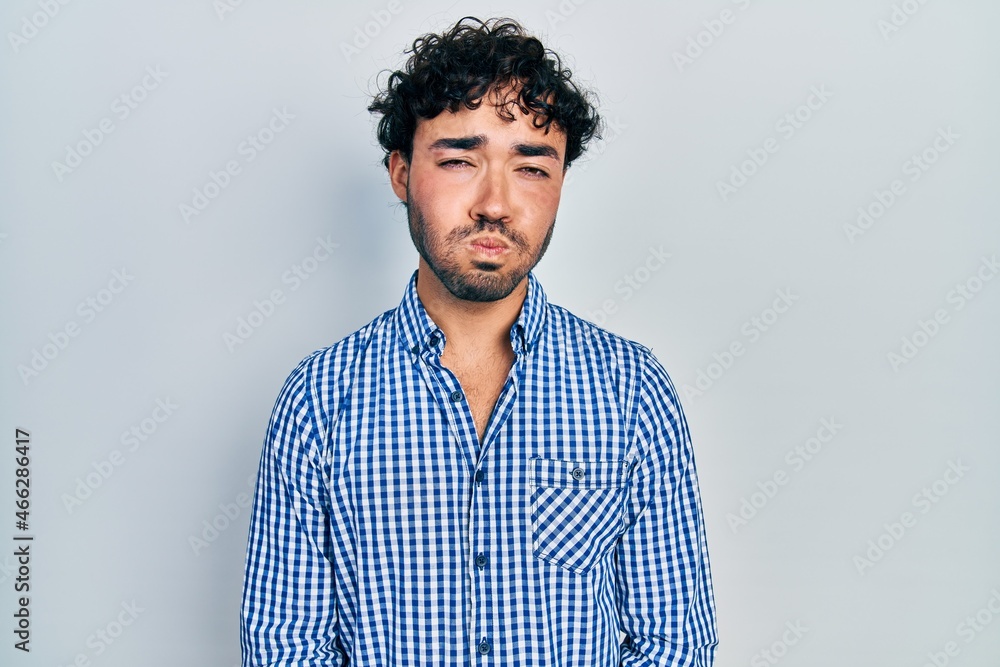 Obraz premium Young hispanic man wearing casual clothes puffing cheeks with funny face. mouth inflated with air, crazy expression.