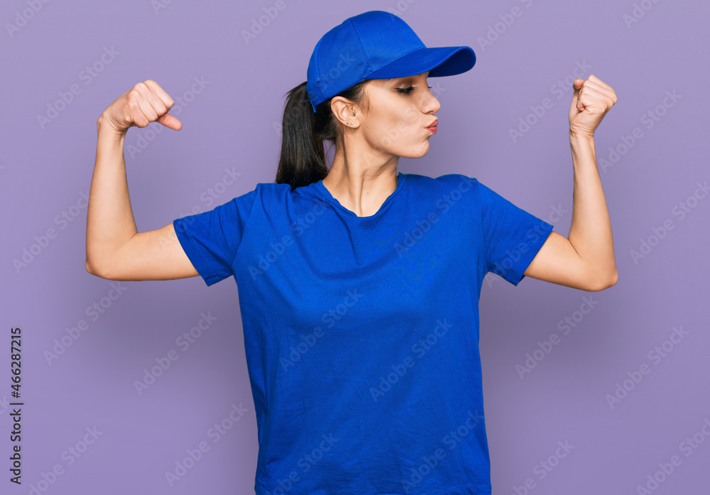 Young hispanic girl wearing delivery courier uniform showing arms muscles smiling proud. fitness concept. Young hispanic girl wearing delivery courier uniform showing arms muscles smiling proud. fitness concept.