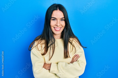 Young brunette woman wearing casual sweatshirt happy face smiling with crossed arms looking at the camera. positive person.