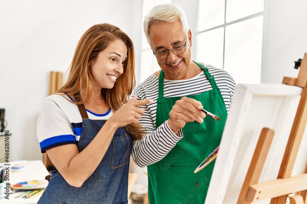 Fototapeta premium Middle age paint teacher and student smiling happy painting at art studio.