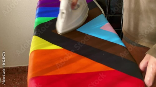 Close-up of anonymous adult in underwear ironing a lgtbi+ flag on an ironing board. Housework photo