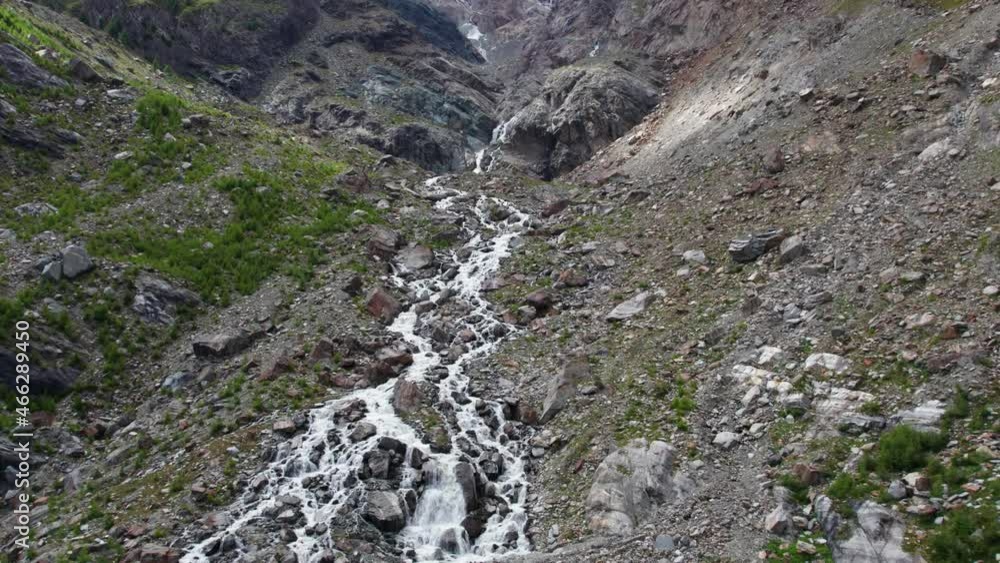 aerial flight up a massive mountain formation with wild waterfall and river, breathtaking drone shot in the swiss alps in saas-fee aerial flight up a massive mountain formation with wild waterfall and river, breathtaking drone shot in the swiss alps in saas-fee