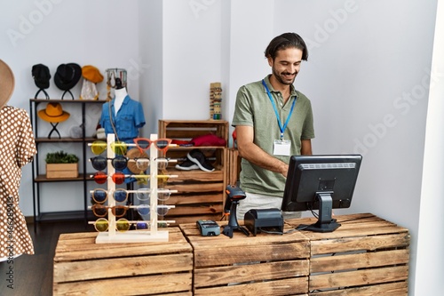 Handsome hispanic man working as shop assistance at retail shop