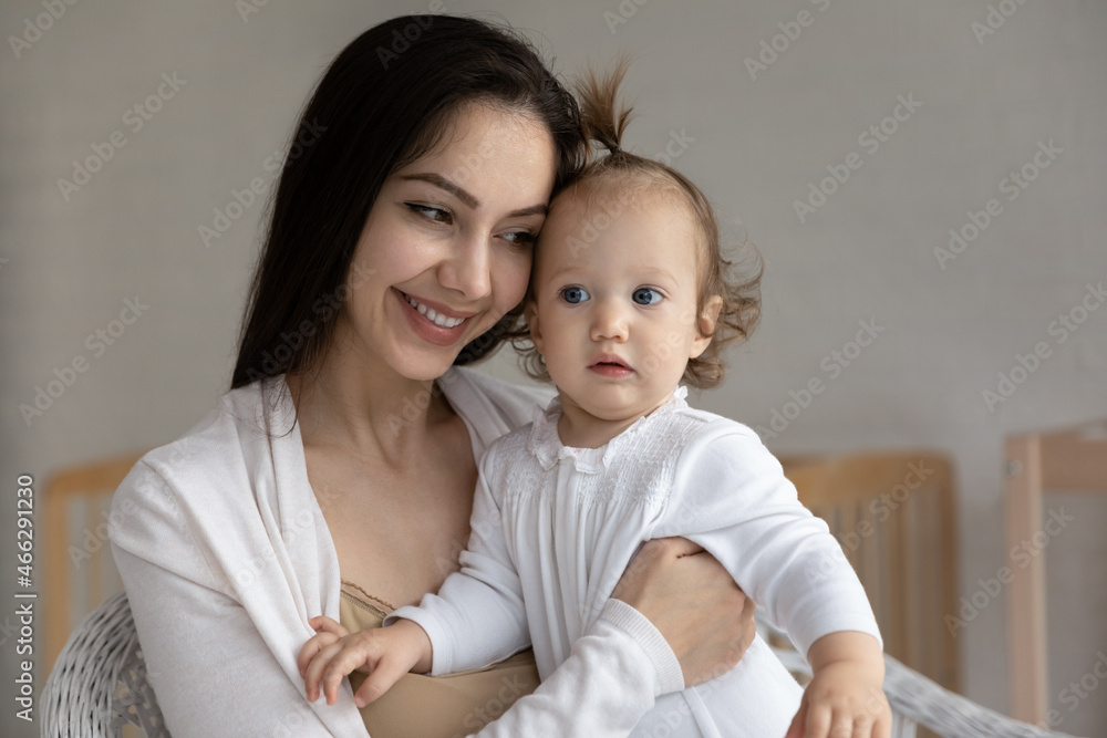 Head shot close up happy loving young mother hugging small daughter, smiling caring mom holding adorable little girl child toddler, family enjoying tender moment at home, motherhood concept Head shot close up happy loving young mother hugging small daughter, smiling caring mom holding adorable little girl child toddler, family enjoying tender moment at home, motherhood concept