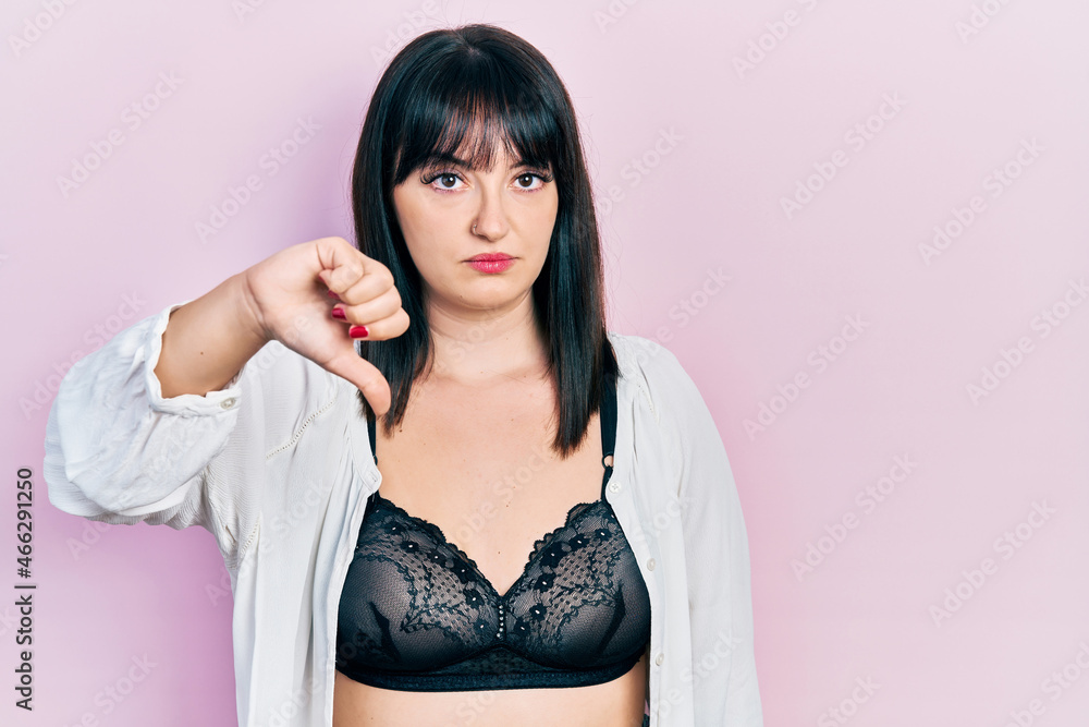 Young hispanic woman wearing lingerie looking unhappy and angry showing rejection and negative with thumbs down gesture. bad expression. Young hispanic woman wearing lingerie looking unhappy and angry showing rejection and negative with thumbs down gesture. bad expression.