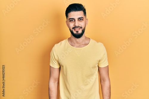 Handsome man with beard wearing casual yellow t shirt with a happy and cool smile on face. lucky person.