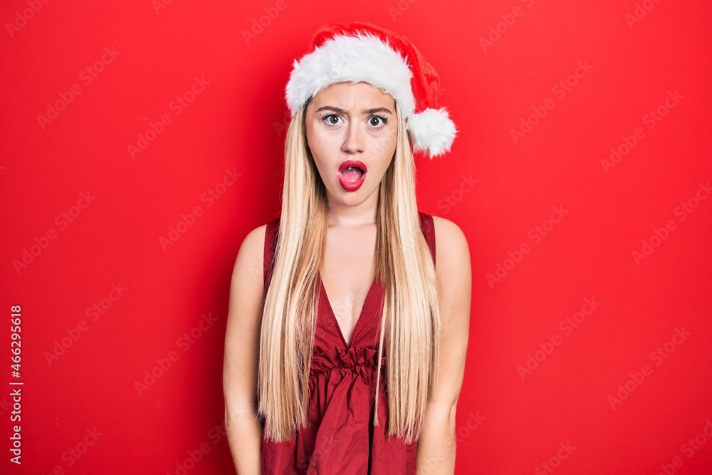 Young blonde girl wearing christmas hat afraid and shocked with surprise expression, fear and excited face. Young blonde girl wearing christmas hat afraid and shocked with surprise expression, fear and excited face.
