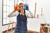 Young caucasian woman smiling confident showing painted palm hands at art studio