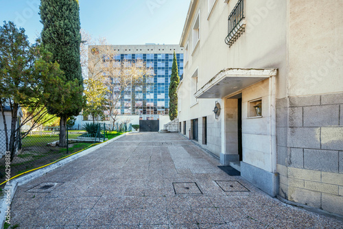 River stone conglomerate tile pavement with office building facade in the background and garden with trees
