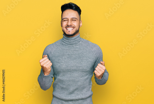 Canvas Print Young arab man wearing casual clothes very happy and excited doing winner gesture with arms raised, smiling and screaming for success