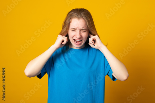 Annoyed female wearing blue t-shirt with furious expression, covering her ears being angry, screaming. Negative human emotions, reaction, attitude concept. © Eugene