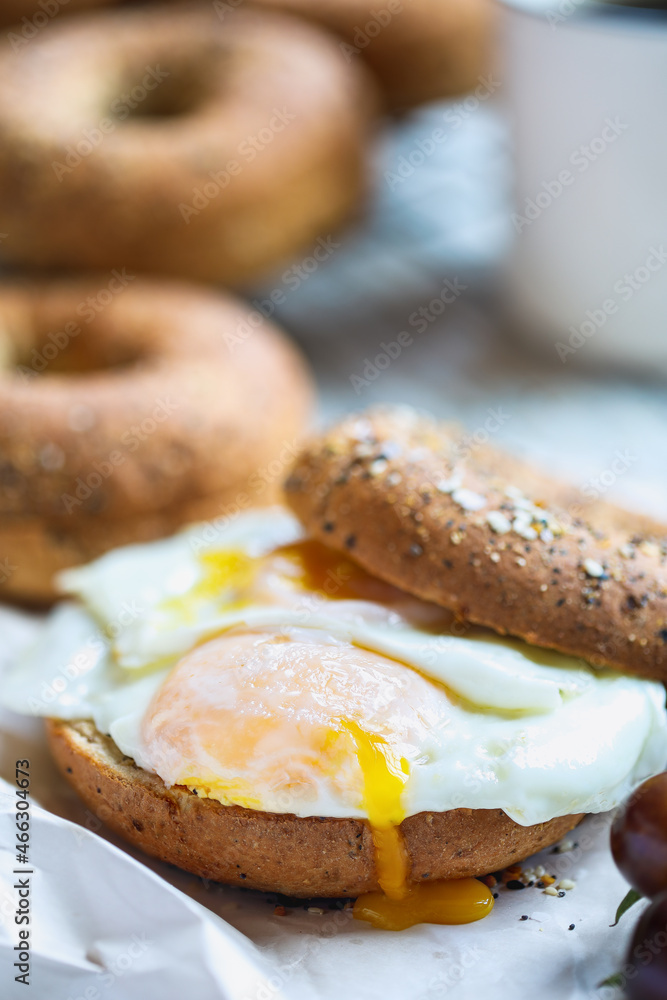 Fresh healthy bagel sandwich with sunny side up fried egg with black coffee. Healthy diet food. Selective focus with blurred background. Fresh healthy bagel sandwich with sunny side up fried egg with black coffee. Healthy diet food. Selective focus with blurred background.