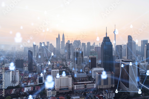 Hologram of social media icons over sunset panoramic cityscape of Kuala Lumpur, Malaysia, Asia. The concept of people connections and career opportunities in KL. Multi exposure.