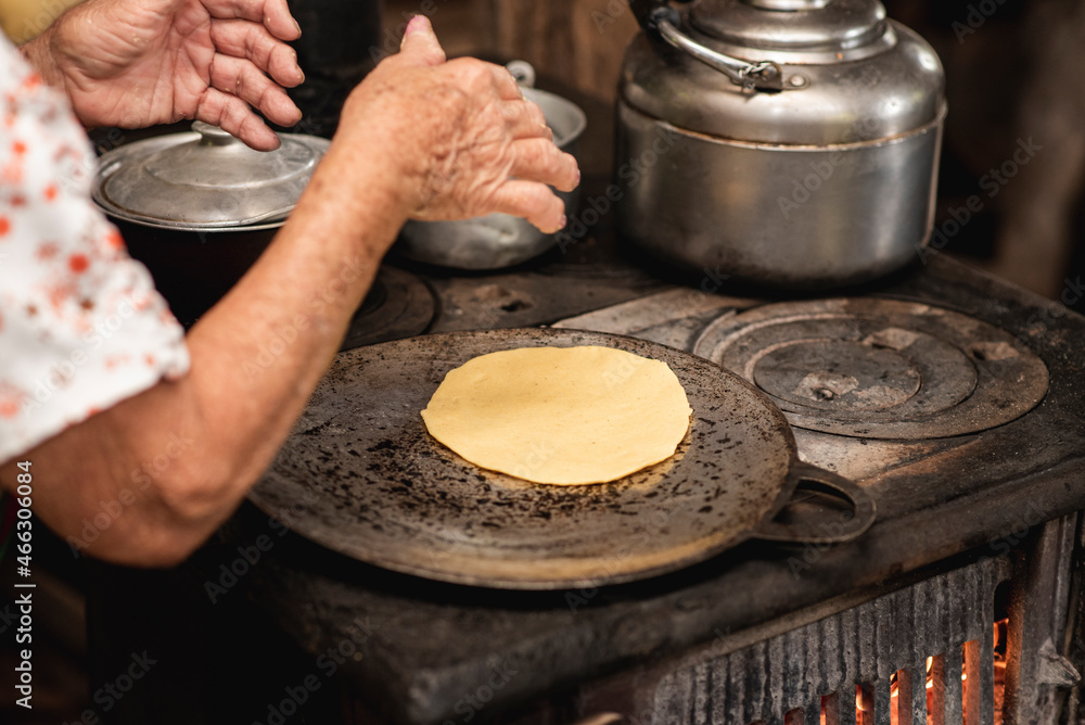 Mano de una mujer adulta mayor cocinando tortillas caseras de costa
