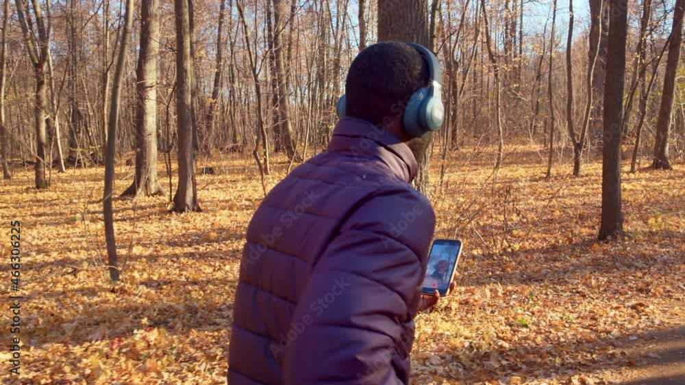 A man dressed in warm clothes shoots himself on camera while jogging. Beautiful forest in the background, the ground near the trees covered with fallen yellow leaves. High quality. 4k footage. A man dressed in warm clothes shoots himself on camera while jogging. Beautiful forest in the background, the ground near the trees covered with fallen yellow leaves. High quality. 4k footage.