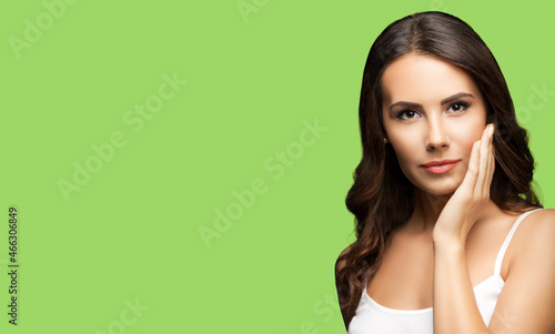 Portrait of beautiful woman in white casual tank top, on light green background. Brunette lovely girl at studio fashion concept. Wide horizontal composition image.