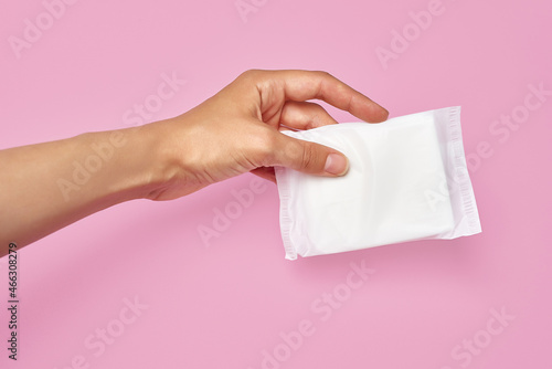 sanitary napkin pad made of cotton in female hand on pink background