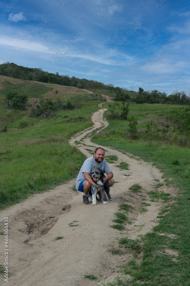 Young man with his dog walking and observing nature on a mountain in the city of Rio de Janeiro, Brazil. Young man with his dog walking and observing nature on a mountain in the city of Rio de Janeiro, Brazil.