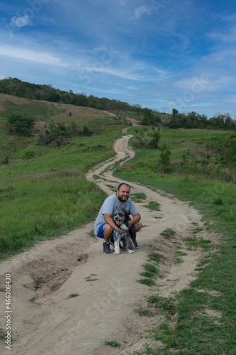 Young man with his dog walking and observing nature on a mountain in the city of Rio de Janeiro, Brazil.