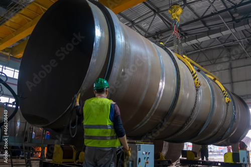 Moving pipes inside the workshop with an overhead crane using a traverse.