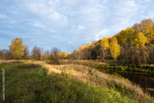 Autumn landscape with a small river and a bank with thick  tall and dry grass.