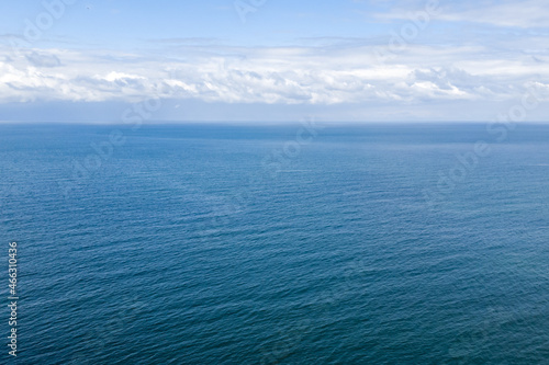 A breathtaking top view of the blue sky with low soaring gray clouds on the blue sea surface. Light breeze, copy space. Long awaited vacation, rest and travel concept