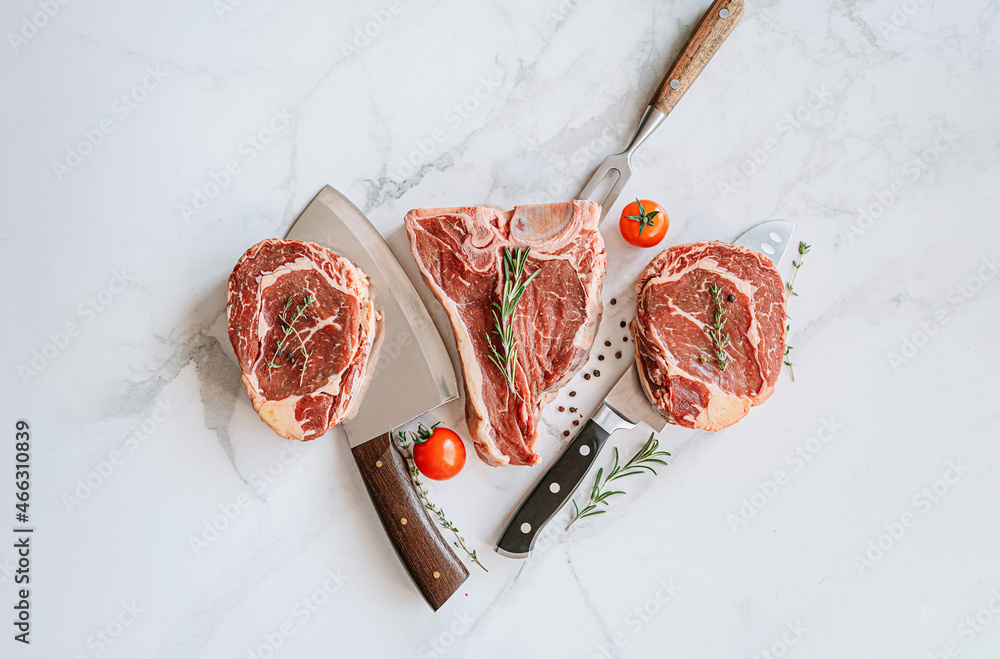 three delicious steaks ready to grill on a white marble surface