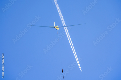 a glider is pulled into the sky with condensation stripes in background