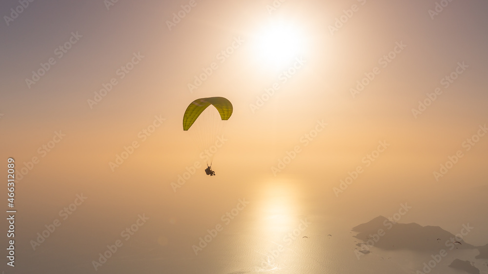 Silhouette of tandem paragliders in the evening on the sunset