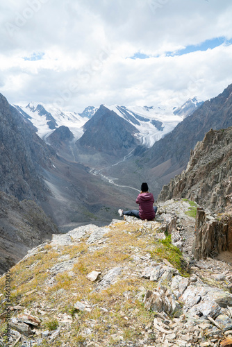 sports girl in a bright hat sits on the top of the mountain