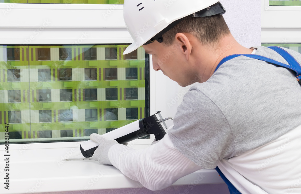 the worker seals the seams of the windows in the room the worker seals the seams of the windows in the room