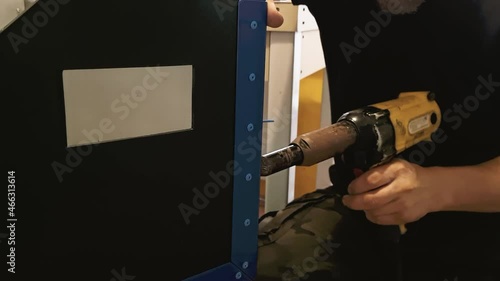 Male mechanic works with pneumatic tool rivet gun. Hands hold electric riveting machine. Blind rivets for metal working. Slow motion. photo