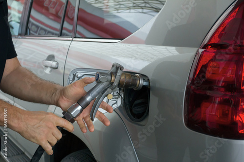 Close-up of a mens hand refilling the car with a gas pump. Man inserting nozzle in fuel cap of a car © proxima13