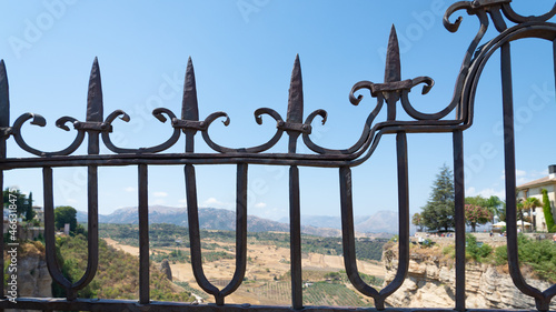 Iron fence on the famous bridge of Ronda, Andalusia, Spain, named "Puente Nuevo" (meaning: new bridge). Beautiful landscape on the background, with blue sky.