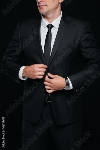 A handsome young man wears a stylish black suit and smiles on a black background. Clean up, prepare.