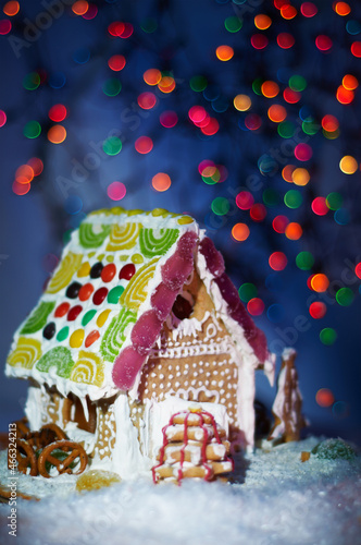 Gingerbread house on the Christmas table with copy space. Living room with Christmas lights. Holiday mood.