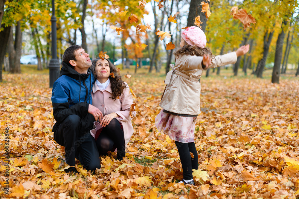 Family portrait in an autumn park. Happy people playing with fallen yellow leaves. Family portrait in an autumn park. Happy people playing with fallen yellow leaves.