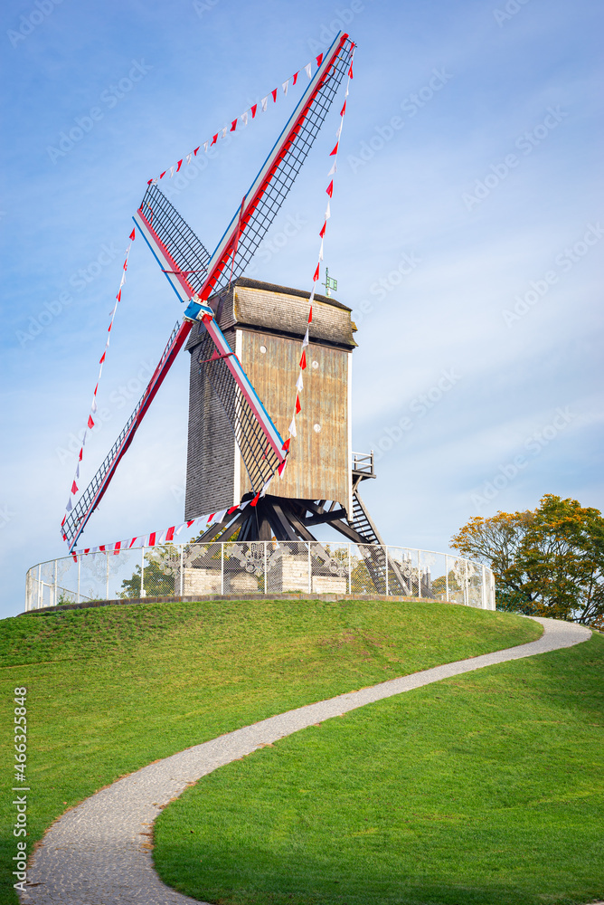 Obraz premium Traditional windmill on rampart Kruisvest in the historic town of Brugge, Belgium. Name of the windmill is Sint-Janshuismolen.