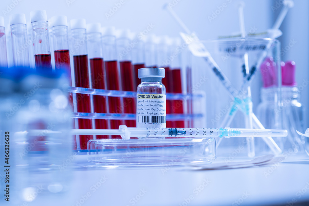 Glass bottle vial and syringe with Covid-19 Coronavirus vaccine in a research medical facility lab. Ampoules with cure on the medical worker laboratory table. Sars-cov-2 pandemic concept. Glass bottle vial and syringe with Covid-19 Coronavirus vaccine in a research medical facility lab. Ampoules with cure on the medical worker laboratory table. Sars-cov-2 pandemic concept.