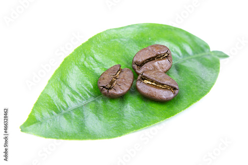 Roasted coffee beans isolated on a white background. Green leaves and scattered coffee beans